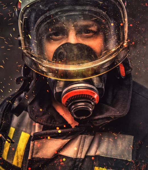 Portrait of firefighter in oxygen mask in a sparks.